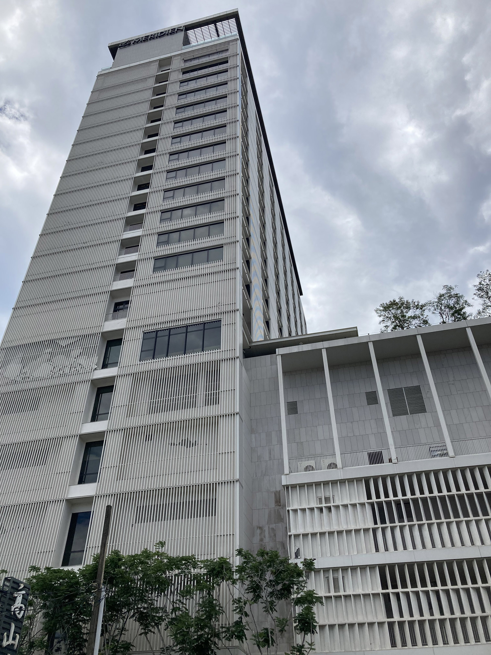 l'hotel méridien est récent (2019) et a une fome irrégulière en élévation. au niveau du chagement d'inertie, les dégats dans les panneaux béton de remplissage (structure poteau-poutres acier/béton) sont fissurés, on note aussi l'accumulation de débrit derrière les brsie soleil (danger pour la voie publique)